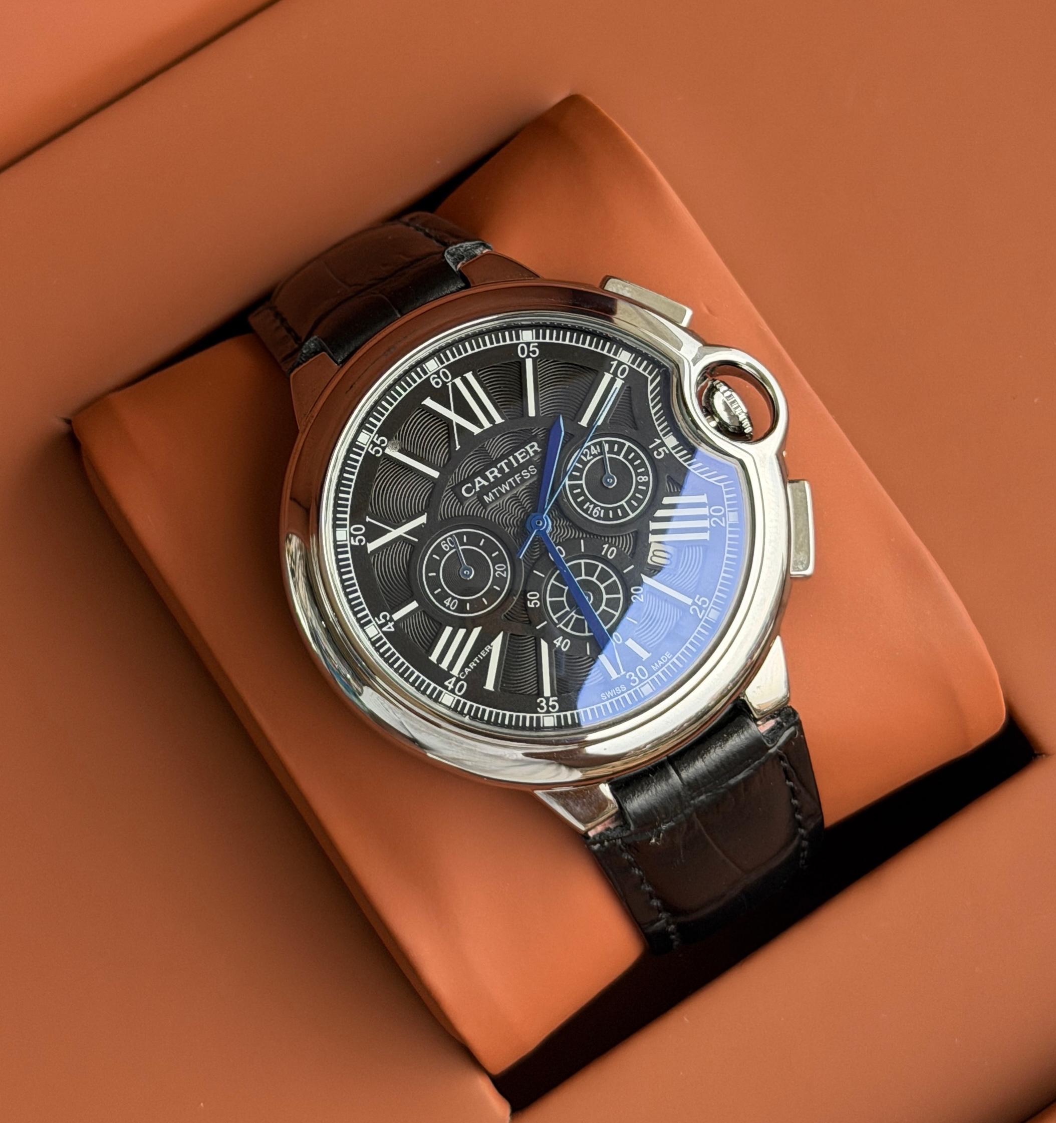 Black dial watch photographed on a warm display cushion